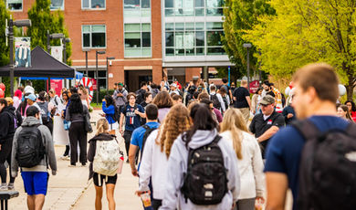 Students walk on a sidewalk through University Park.