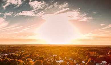 A photo taken by a drone showing the sun above a neighborhood
