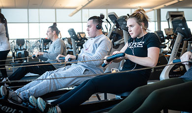 Three students use an exercise machine.