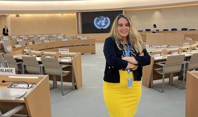 Tiana wears a yellow skirt standing in the assembly room in the United Nations in Geneva 