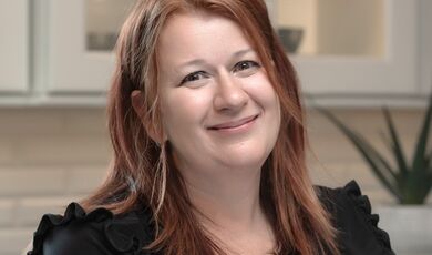 A woman with red hair smiles at the camera