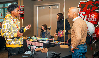 A student and professor converse at a transfer welcome event.
