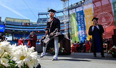 A student shows excitement as he crosses the commencement stage.