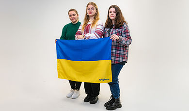 Three Ukrainian students hold their country's blue and yellow flag.
