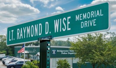 The street sign for Wise Memorial Drive with the police station in the background.