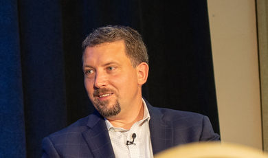 Steve Zuromski sits at the front of a ballroom.