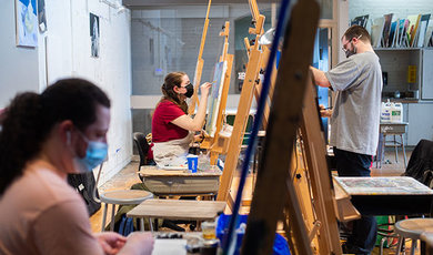 Students painting on canvases in a studio art class