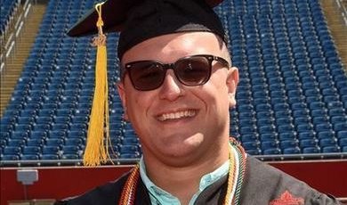 Adam Perez smiling at 2021 BSU graduation in cap and gown wearing honors cords