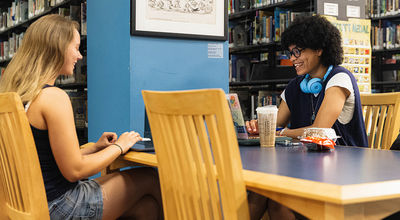 Two students sitting across from each other and studying with laptops in Maxwell Library