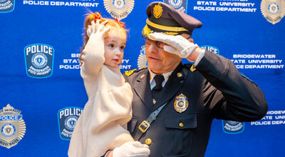 Glen Anderson salutes while holding a young child.