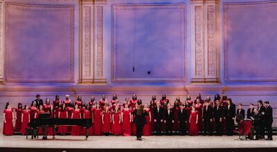 A large choir sings on stage at Carnegie Hall.