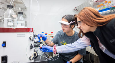 Two students work with a machine in a chemistry lab.