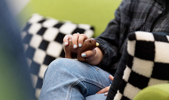A close-up of a student's hand, wearing blue nail polish, holding a "stress bear" during a counseling session