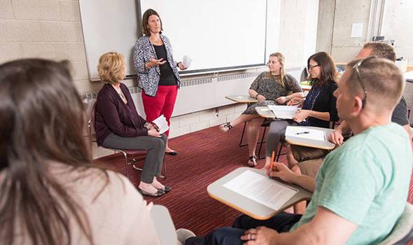 Dr. Katherine Bender teaching a small circle of students in desks