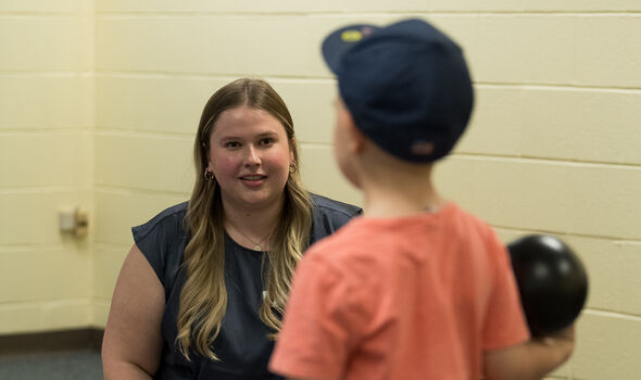 a student smiling and working with a small child