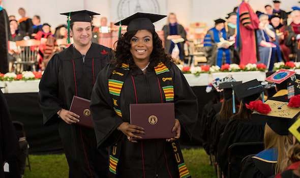 Two students pose with their diplomas