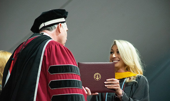 A graudate student recieves her diploma from President Fred Clark