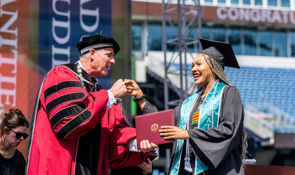 President Clark fist bumping a first generation BSU graduate while handing her her degree