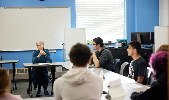 Dr. Susan Eliason sits teaching students in a hollow square desk formation
