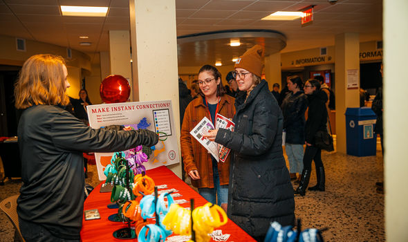 2 transfer students talk to another student behind a table with a sign that says Make