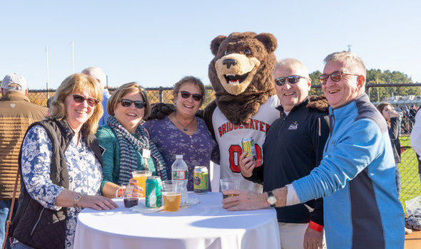 BSU Alumni and mascot Bristaco around a table next to the football field at Homecoming