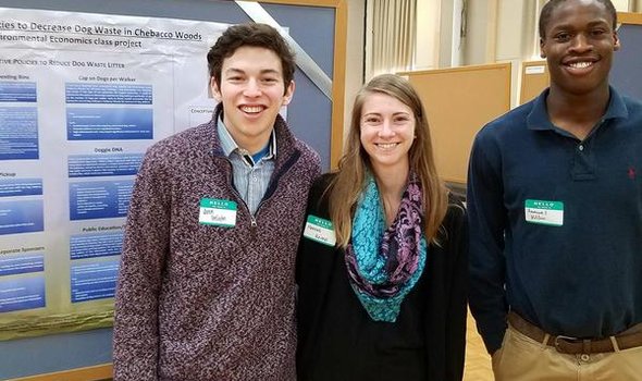 students smiling in front of their environmental symposium project