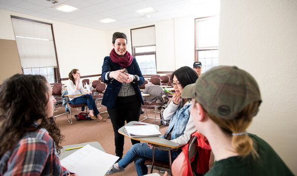 Dr. Sarah Wiggins smiling and gesturing as she talks to a group of students in a history class