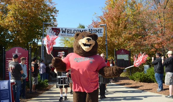 Bristaco the BSU bear mascot under a "welcome home" banner followed by a marching band