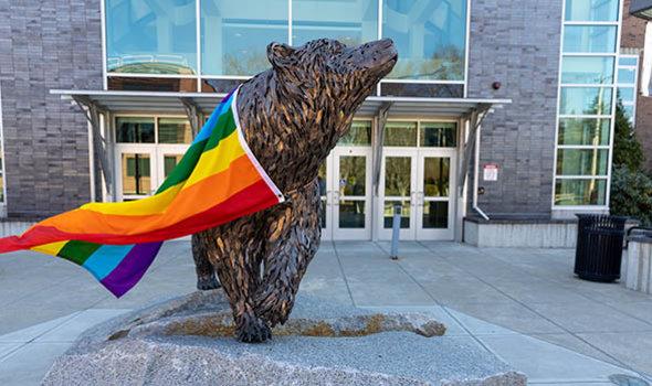 The bear sculpture in front of Rondileau Student Union draped in a Pride flag