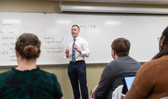BSU professor Kevin Donnelly teaching class in front of a white board as students look on