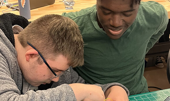 Two students programming a sensor on a work table