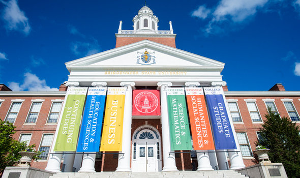 photo of the front of BSU's Boyden Hall with banners of the 6 BSU colleges in front of the portico pillars and the BSU seal in the middle and blue sky above