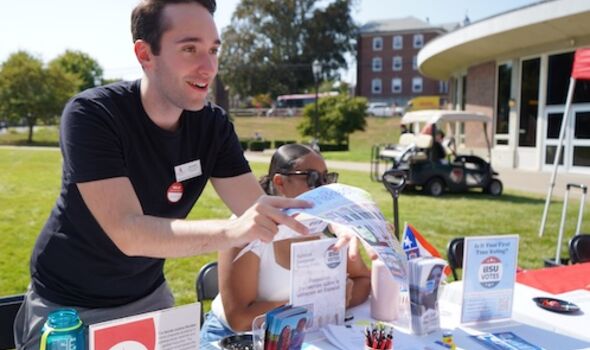 a male student passes out flyers at a voter registration table