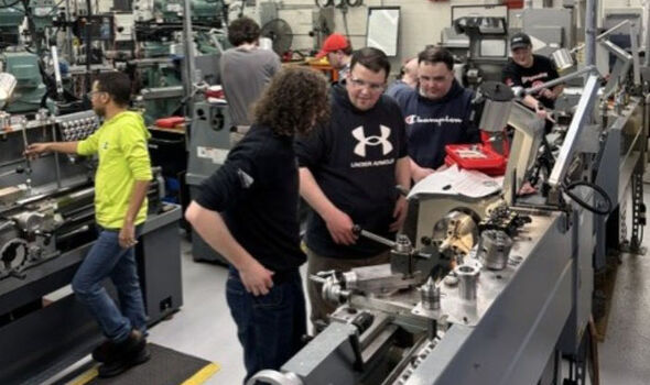 In a machine shop groups of 2-3 people are teaching and learning around 4 different machines