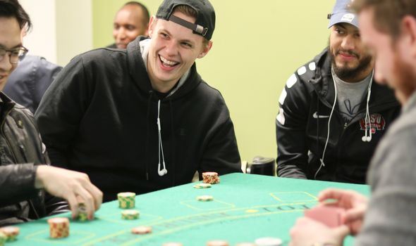 A group of students sit around a card table with stacked chips