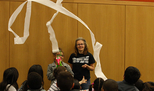 BSU Professor Susan Savill, wearing a t-shirt that says &quot;With enough thrust pigs fly just fine,&quot; has an elementary student demonstrate a gadget that blows air on a roll of toilet paper and makes it unroll into the air