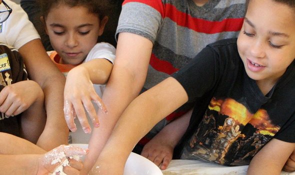 children putting their hands in a bowl