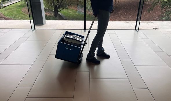 An instructor pulls a rolling caddy filled with science kits