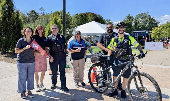 BSU police officers standing and smiling with three members of the BSU community at an event on campus. One officer stands next to a bicycle that he holds.