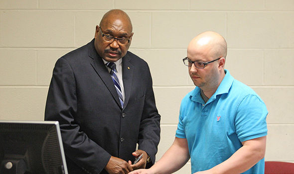 Professor Robert McManus helps a graduate student prepare the computer for a presentation