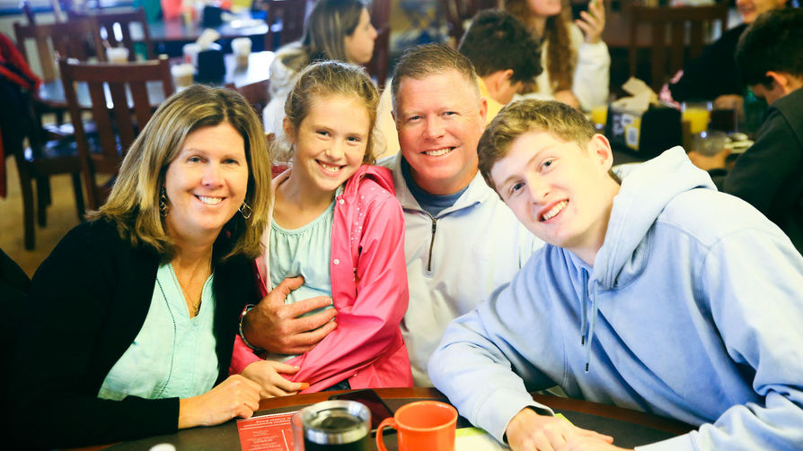 A BSU family (mother, father, son and daughter) smiling at the camera at Homecoming Family Breakfast