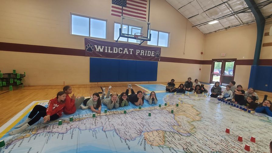 Groups of students posing on a giant floor map