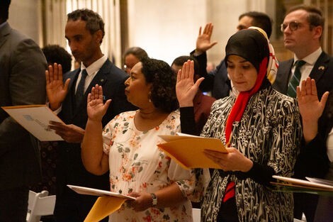 The twenty five inductees to citizenship listen to the speakers before taking the oath of citizenship during the Constitution Day naturalization ceremony in the National Archives Rotunda on Sept. 15, 2023.