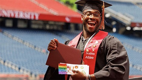 A student holds their diploma and envelope containing money.