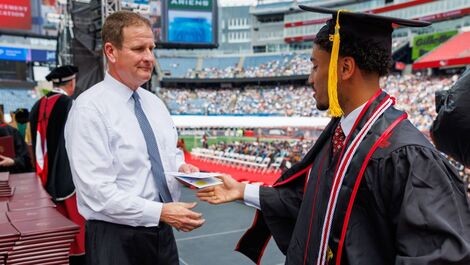 A graduate accepts an envelope with cash from Rob Hale.