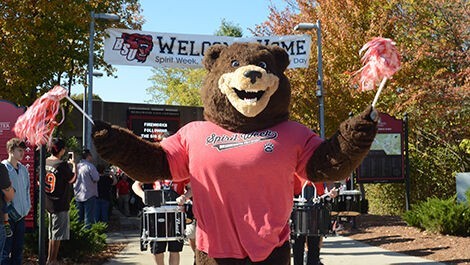 Bristaco walks in front of a drum line waving pom poms.
