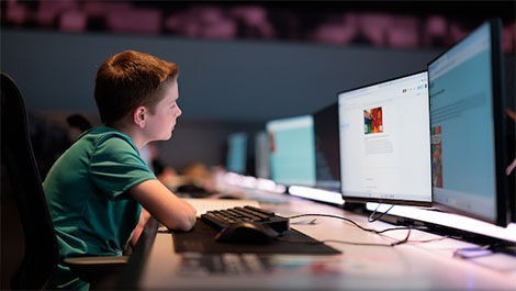 A student works at a computer with dual monitors.