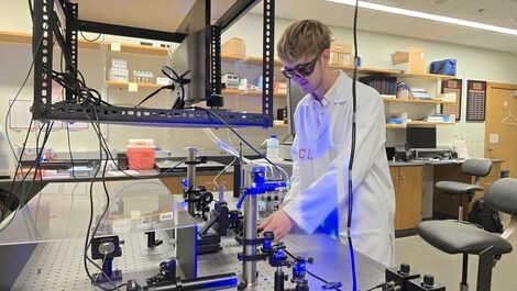Christopher Leary works with optical equipment in a lab.