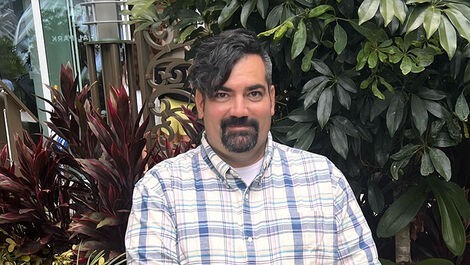 Headshot of Nathan Couto with plants in the background.