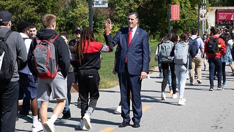 President Clark high fives a student walking along a path.